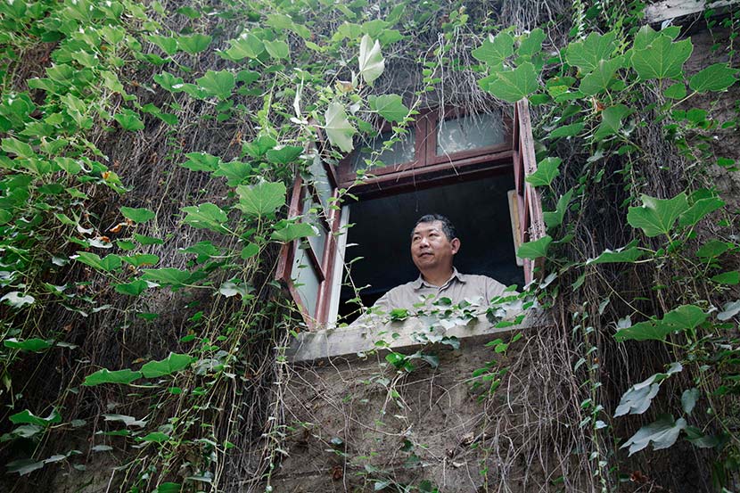 Hu Fusun looks through a window at the house that has belonged to his family for generations, Nanjing, Jiangsu province, July 28, 2017. Wu Huiyuan/Sixth Tone