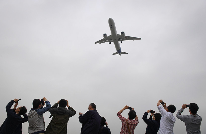 Spectators take photos as they watch the Comac C919, the first Chinese-built large airliner in decades, come in for landing during its maiden flight at Shanghai’s Pudong International Airport, May 5, 2017. Greg Baker/Reuters/VCG