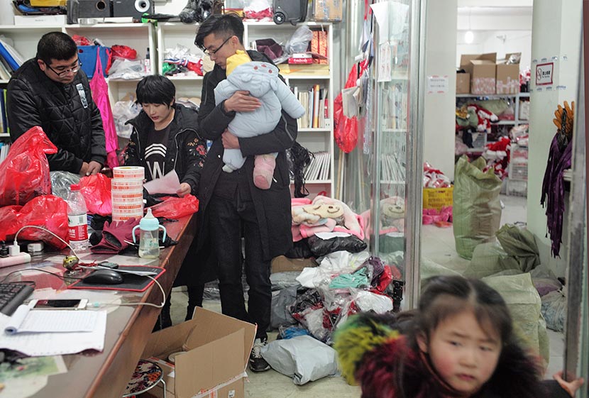 Lei Congrui (center) stands beside his wife at his lingerie warehouse in Guanyun County, Jiangsu province, Dec. 27, 2017. The couple brought their children to work on a busy day at the warehouse. Wu Yue/Sixth Tone