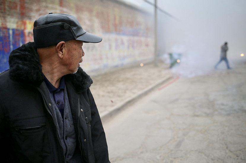 Yang Fengshen watches firecrackers on the main road of Nanyangjiazhuang Village, Dec. 29, 2017. IC
