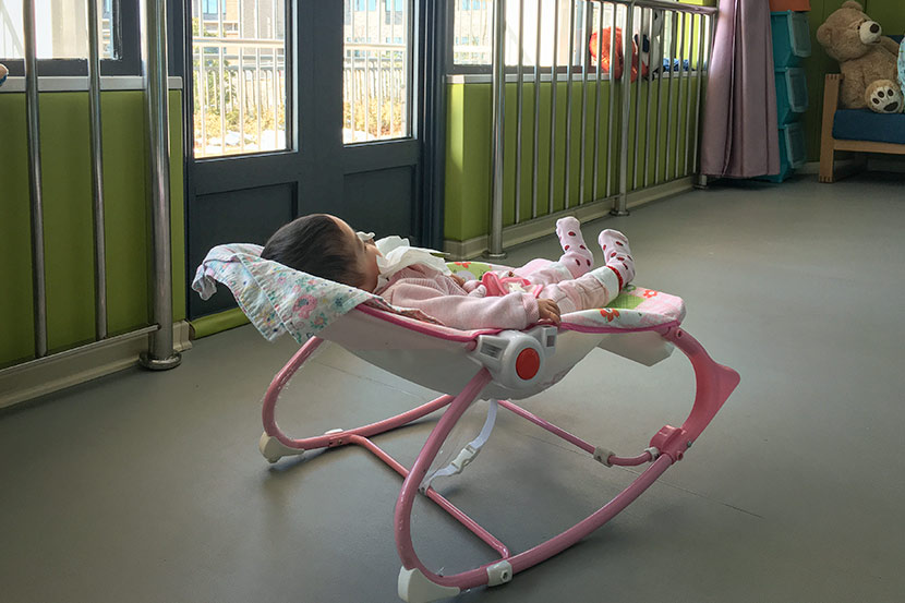 After lunch, a baby girl rests at the Nanjing Rainbow Center, Jiangsu province, Jan. 10, 2018. Ni Dandan/Sixth Tone