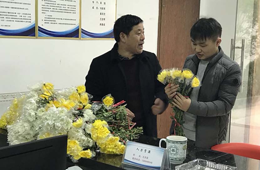 An official gives flowers to a local resident to be used instead of fireworks to commemorate ancestors in Huangcai Town, Hunan province, Feb, 2018. Tan Jun for Sixth Tone