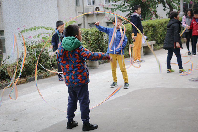 Dyslexic children play with ribbons to improve dexterity in a courtyard next to Weining Dyslexia Education Center in Shenzhen, Guangdong province, Jan. 30, 2018. Cai Yiwen/Sixth Tone