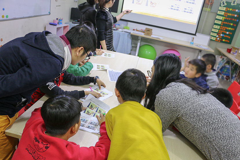 Teachers and volunteers help dyslexic students with schoolwork at Weining Dyslexia Education Center in Shenzhen, Guangdong province, Jan. 30, 2018. Cai Yiwen/Sixth Tone