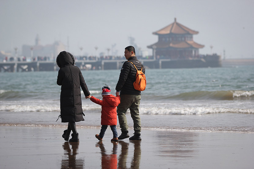 A family of three people visit a tourist spot in Qingdao, Shandong province, Feb. 23, 2018. Huang Xianjie/VCG