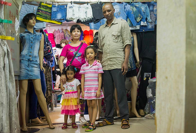 Bah Abdullaye (right), 42, and his Chinese wife pose for a photo with their daughters at their clothing stall in Guangzhou, Guangdong province, July 15, 2014. Dave Tacon/Polaris/VCG