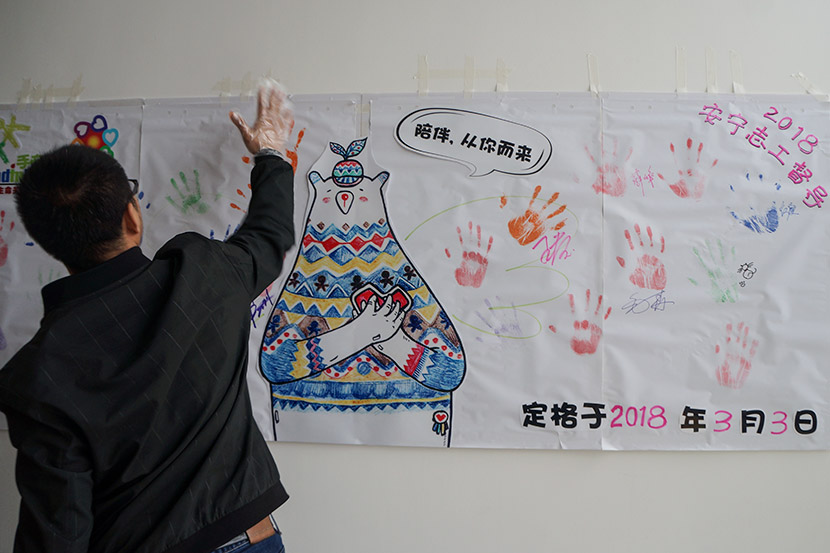 A volunteer puts his handprint on a banner at Hand in Hand’s training event in Shanghai, March 3, 2018. Fan Yiying/Sixth Tone