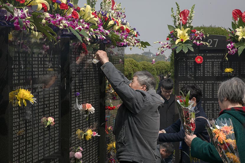 A man places flowers on a monument for people buried at sea in Binhai Ancient Garden Cemetery, Shanghai, March 24, 2018. Shi Yangkun/Sixth Tone