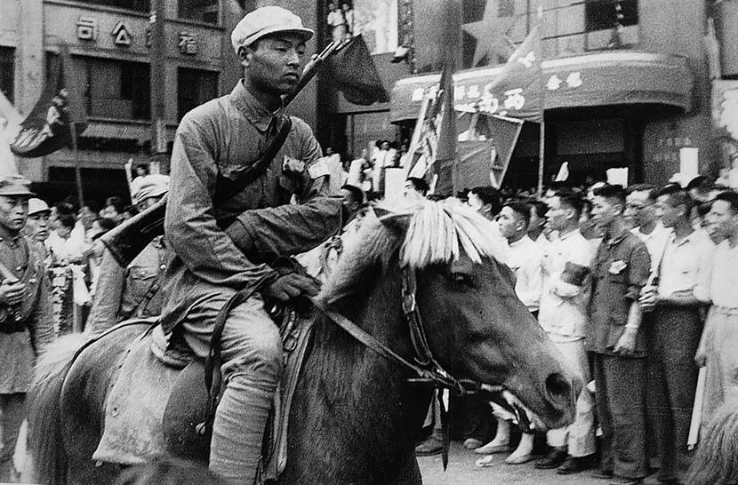 A young soldier rides through downtown Shanghai rides on horseback, while a rifle slings over his back in Shanghai, May 1949. Courtesy of ‘Old Photos’