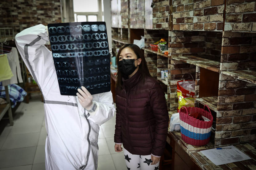 Li Jing, an illustrator, shows her chest X-rays to medical staff at the quarantine center set up in the dormitories of Wuhan Vocational College of Software and Engineering in Wuhan, Hubei province, Feb. 27, 2020.  Zhao Di/China Youth Daily
