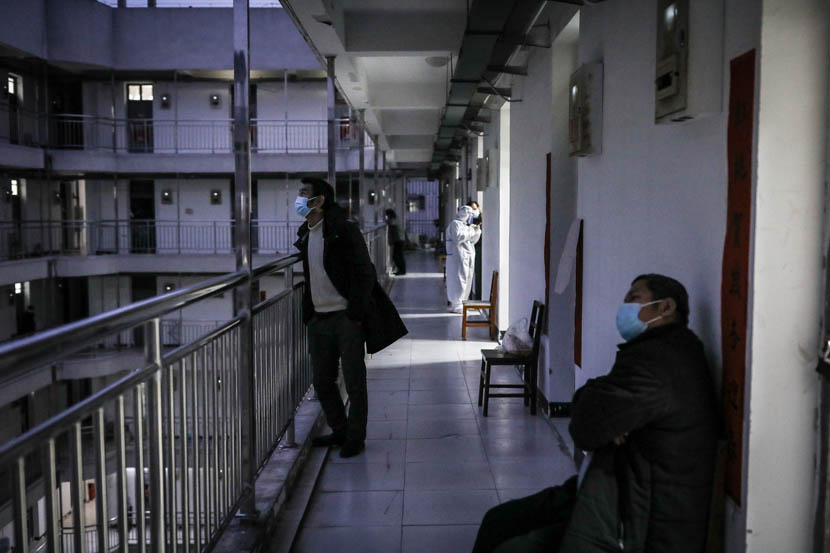 Men rest along the gallery outside their rooms at the quarantine center set up in the dormitories of Wuhan Vocational College of Software and Engineering in Wuhan, Hubei province, March 13, 2020. Zhao Di/China Youth Daily
