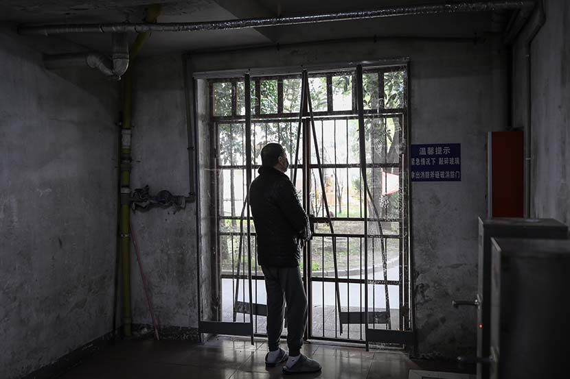 A man looks through a locked door at the quarantine center set up in the dormitories of Hubei University in Wuhan, Hubei province, March 14, 2020. Zhao Di/China Youth Daily
