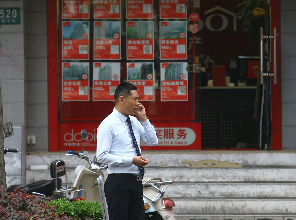 A real estate agent talks on the phone in Shanghai, 2015. IC