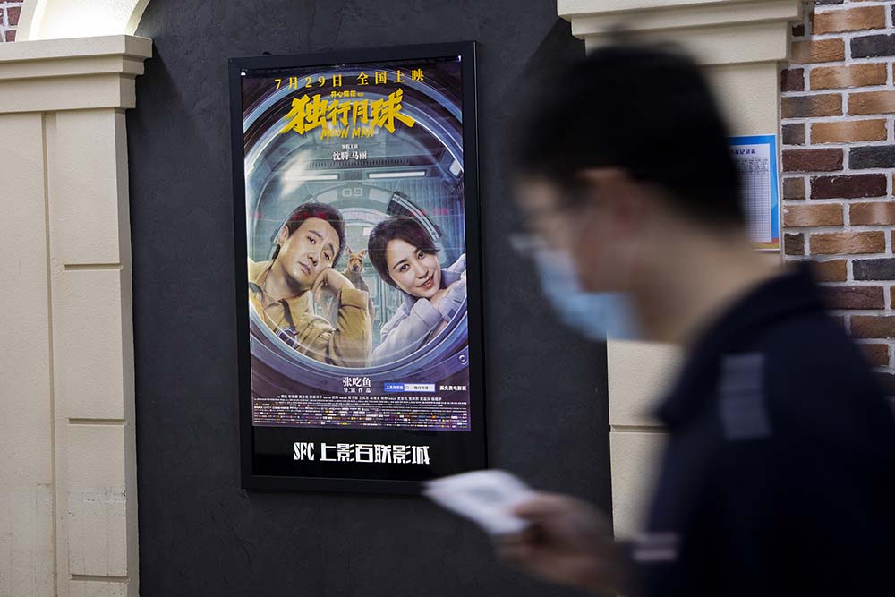 A man walks past a promotional poster for 