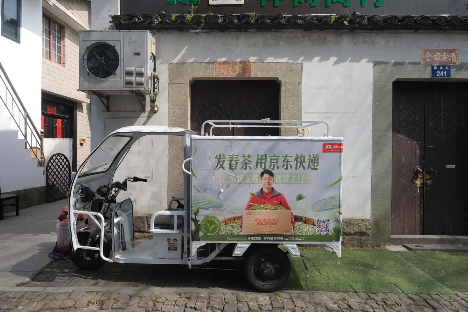 A delivery vehicle stops along the village road to collect tea leaves from local producers.