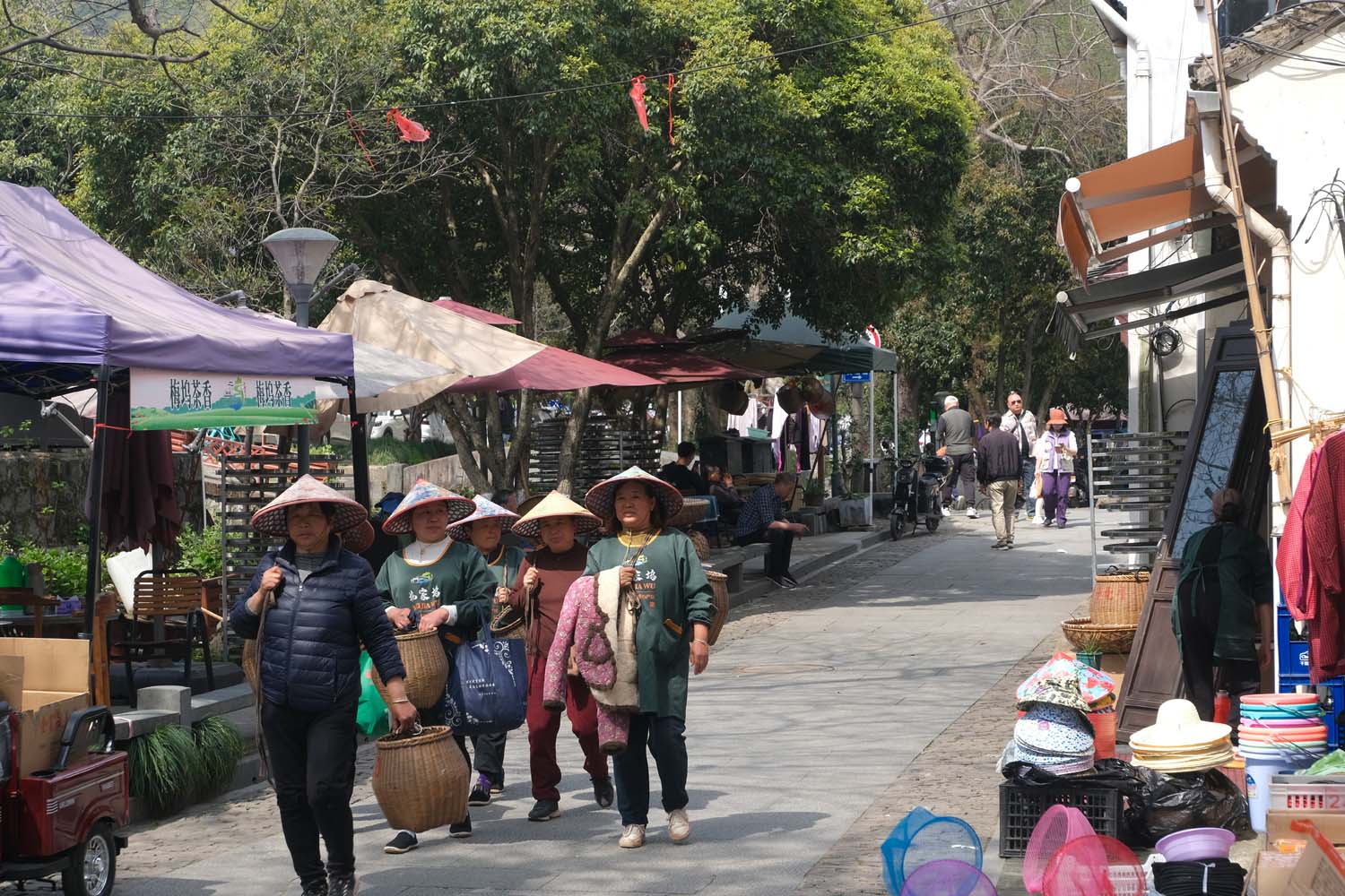 Tea pickers walk through Meijiawu with bamboo baskets.